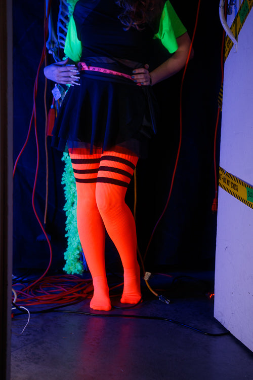 A person wearing Electric Shock thigh highs in neon orange with black stripes