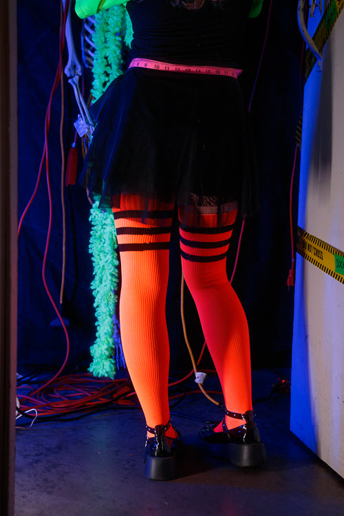 A person wearing Electric Shock thigh highs in neon orange with black stripes