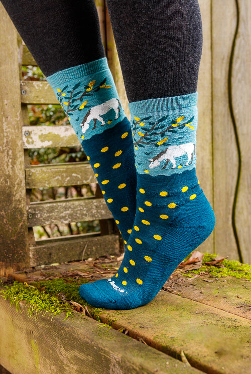 A person wearing unicorn wildlife crew socks in dark teal