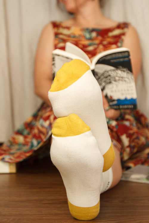 A Person Wearing Out Of Print Bookworm Crew Socks, in cream