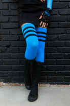 A person wearing Electric Shock thigh highs in neon blue with black stripes