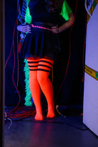 A person wearing Electric Shock thigh highs in neon orange with black stripes