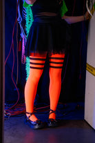 A person wearing Electric Shock thigh highs in neon orange with black stripes