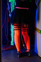 A person wearing Electric Shock thigh highs in neon orange with black stripes
