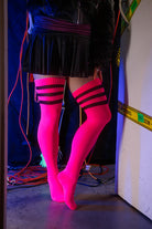 A person wearing Electric Shock thigh highs in neon pink with black stripes