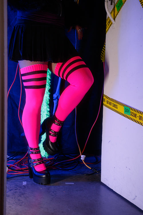 A person wearing Electric Shock thigh highs in neon pink with black stripes