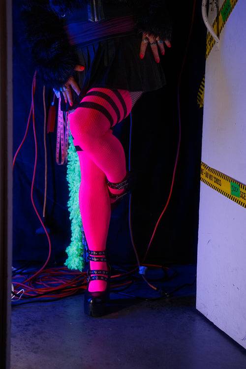 A person wearing Electric Shock thigh highs in neon pink with black stripes