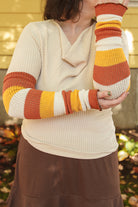 A person wearing Candy Corn striped warmers