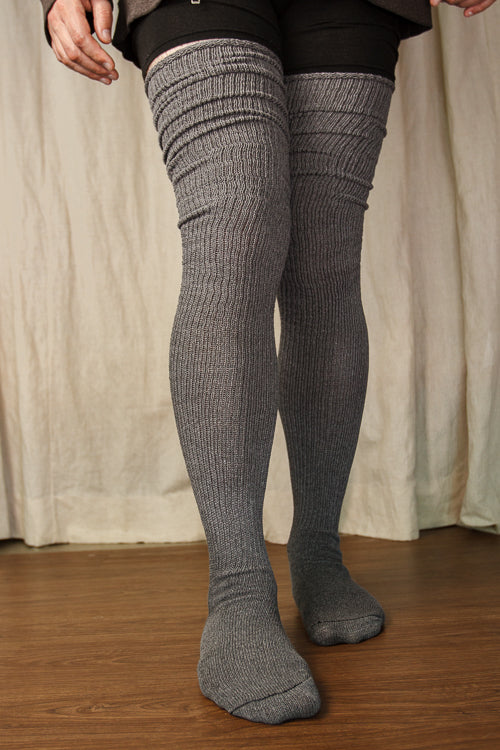 A person wearing larger-footed long cuffable scrunchable socks in charcoal