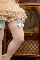 A person wearing opaque thigh high stockings in white with a light blue bow
