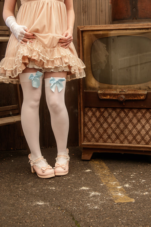 A person wearing opaque thigh high stockings in white with a light blue bow