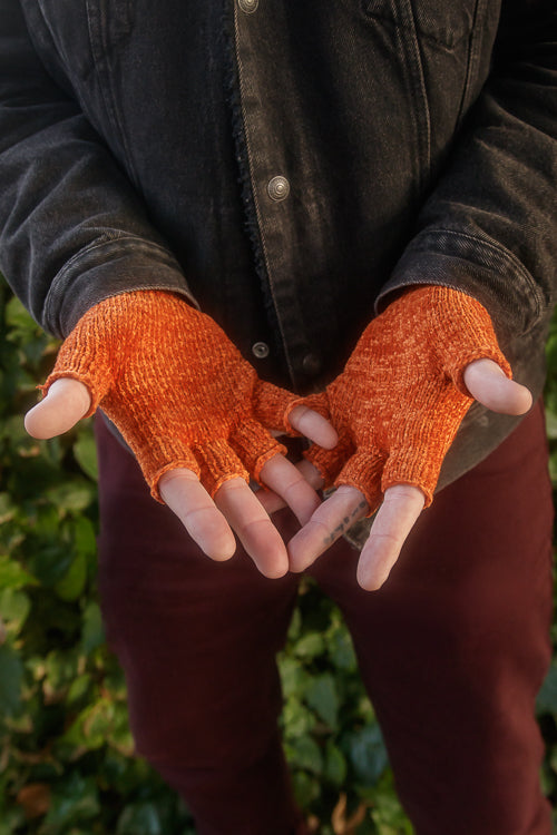 A person wearing chenille fingerless gloves in pumpkin