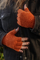 A person wearing chenille fingerless gloves in pumpkin